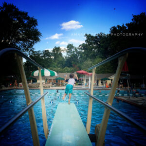 little boy in blue bathing suit jumping off a diving board