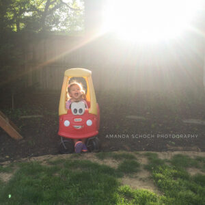 Little boy plays in toy car in backyard with snuffler
