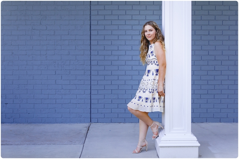 Senior Portrait in Sarasota of girl in blue and white dress in front of a blue brick wall