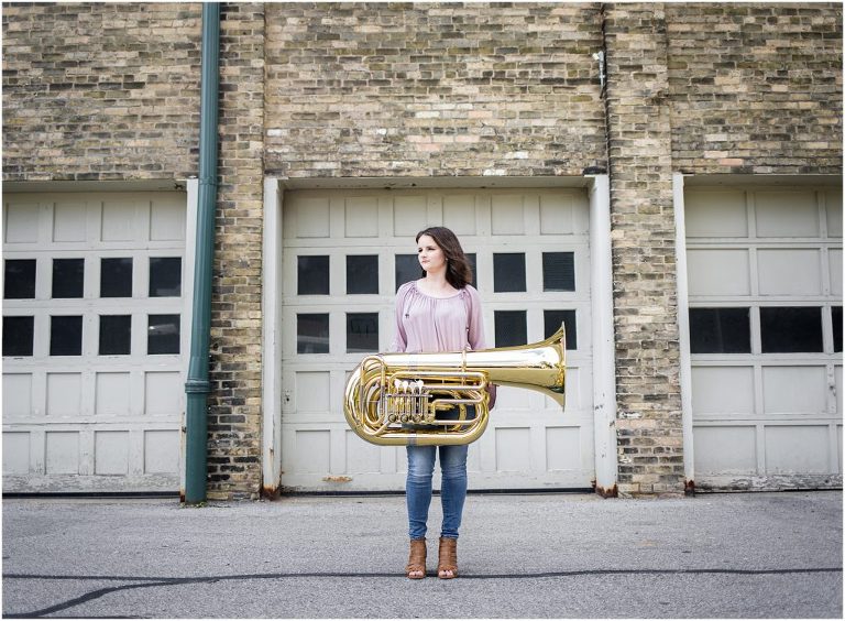 Girl in pink top holding a tuba for high school senior portrait