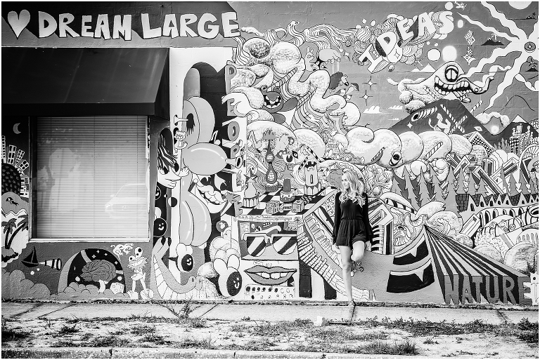 Black and white image of woman standing in front of a large mural in the Sarasota Rosemary District-by-Michaela-Ristaino-Photography_0006.jpg
