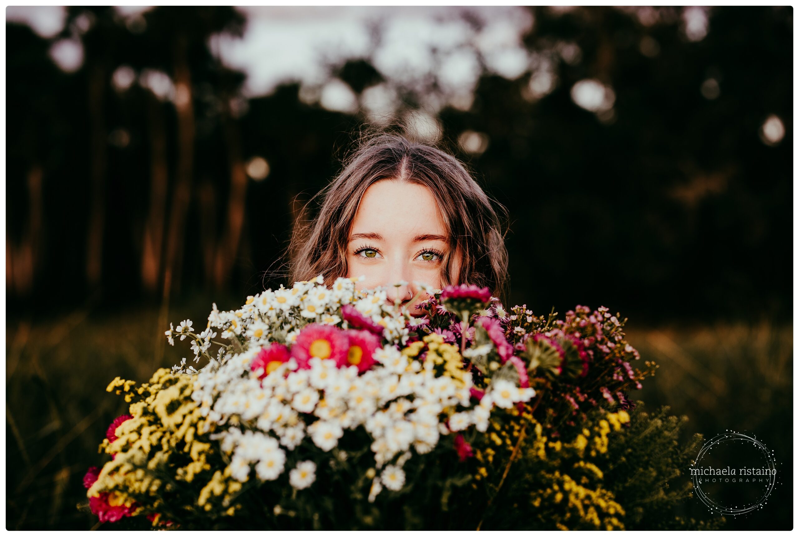 Sarasota senior girl holding wildflowers barefoot in field at Myakka River State Park during sunset.