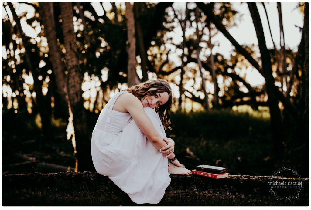 Sarasota teen girl in white dress poses with antique books in Myakka River State Park. Best Outdoor Senior Photo Spots in Sarasota