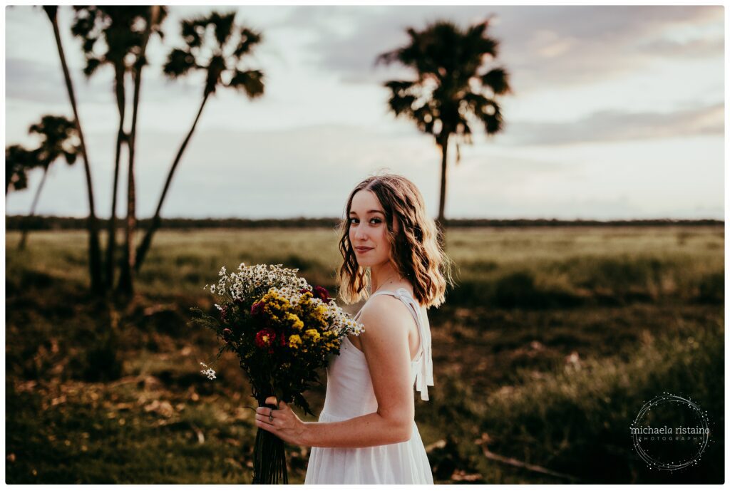 Senior silhouette standing in vast grassy field at golden hour in Sarasota.