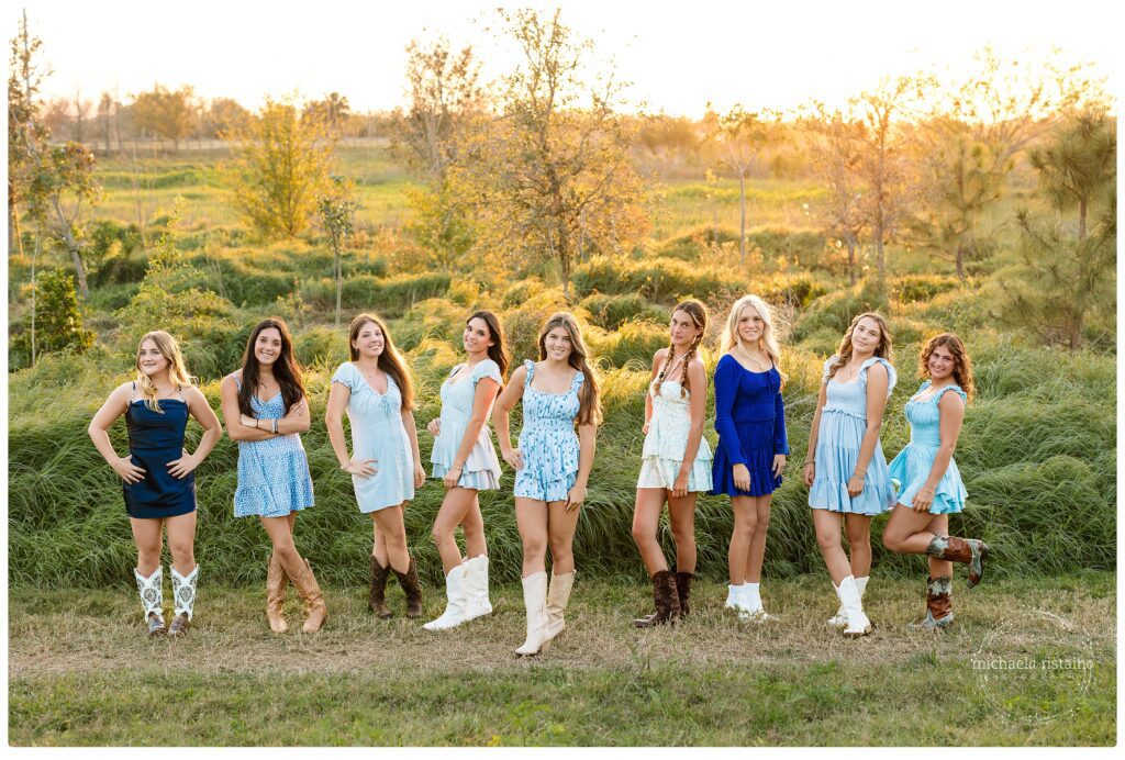Group of teen girls in coordinating dresses and boots posing together in a sunlit field, celebrating friendship and connection through a Sarasota photography session.