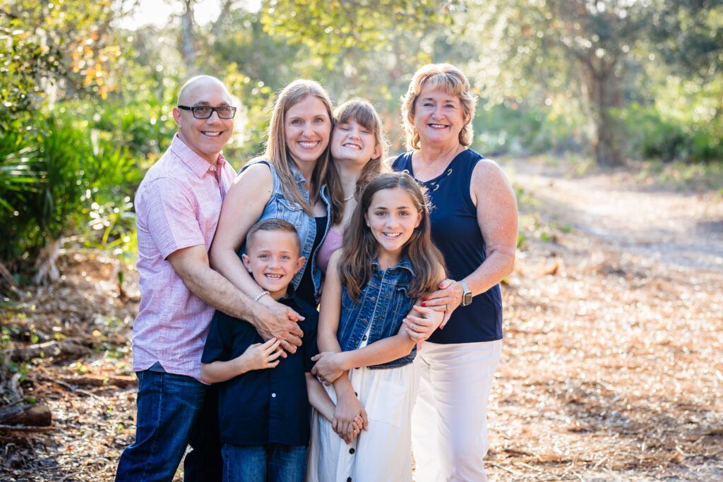 Extended family group hugging and smiling outdoors in Sarasota during a family photography session.