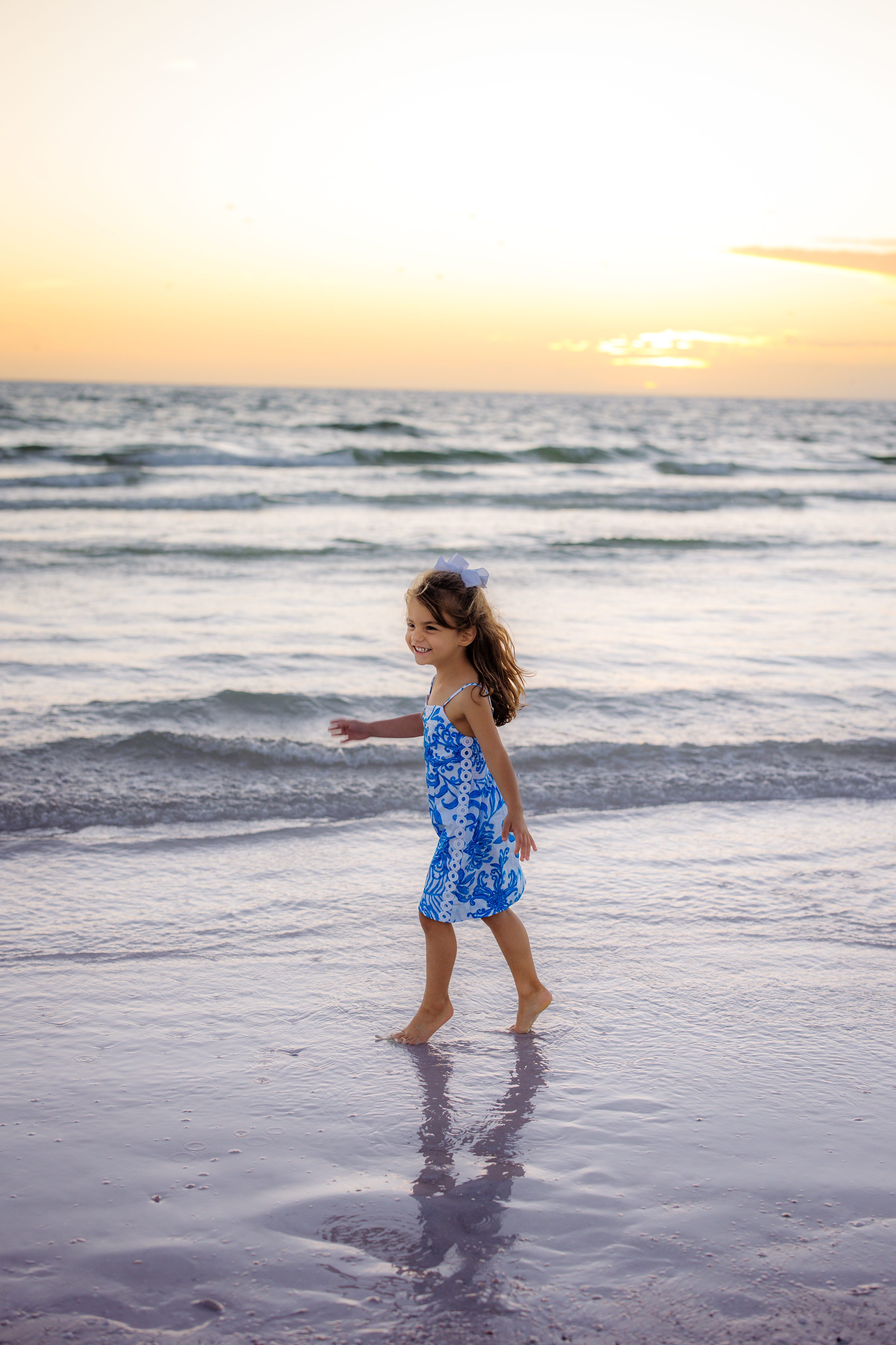 Smiling young girl walking barefoot along the shoreline at Siesta Key Beach during a Sarasota family photo session