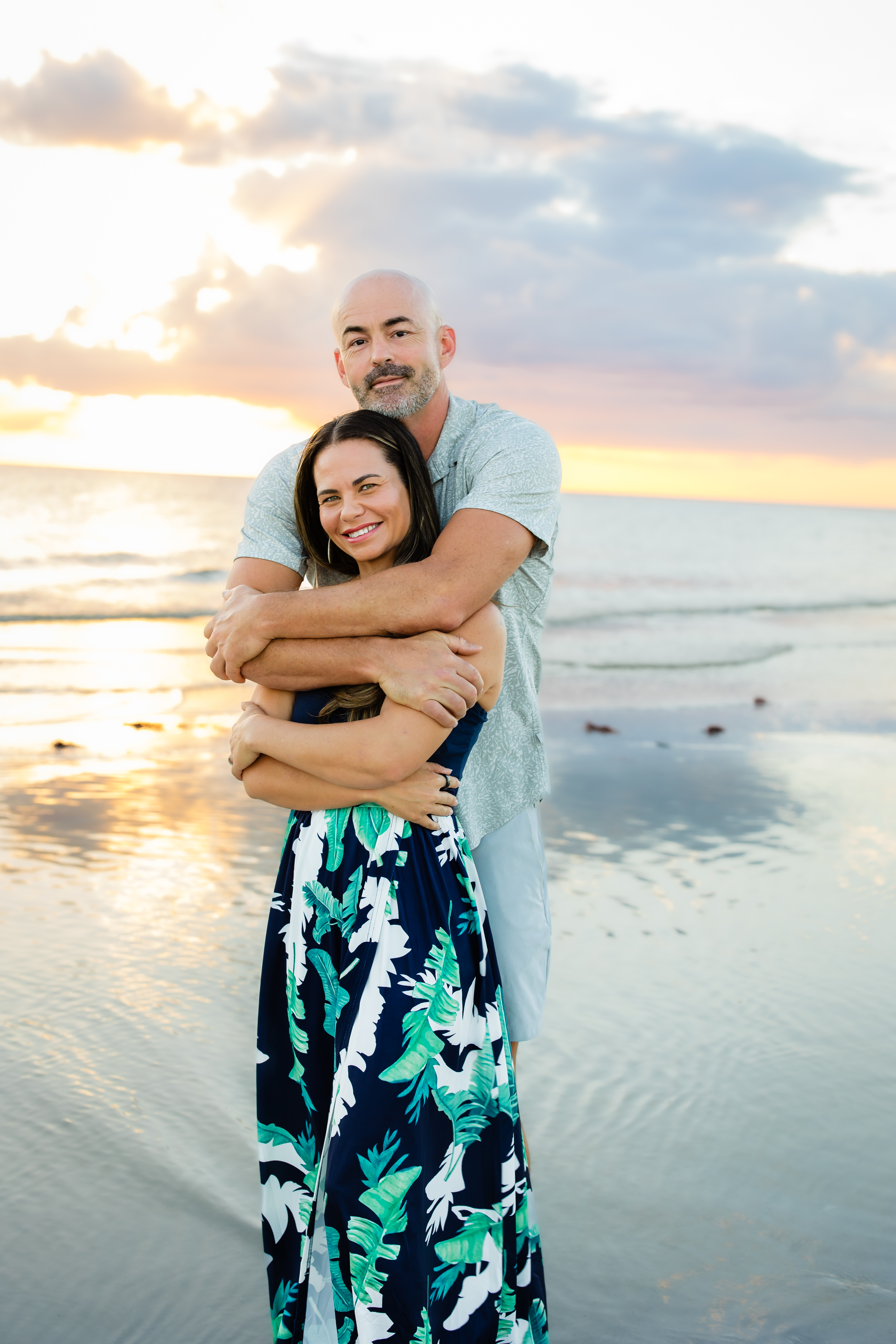 Couple hugging and smiling on the beach at golden hour during a Sarasota mini session