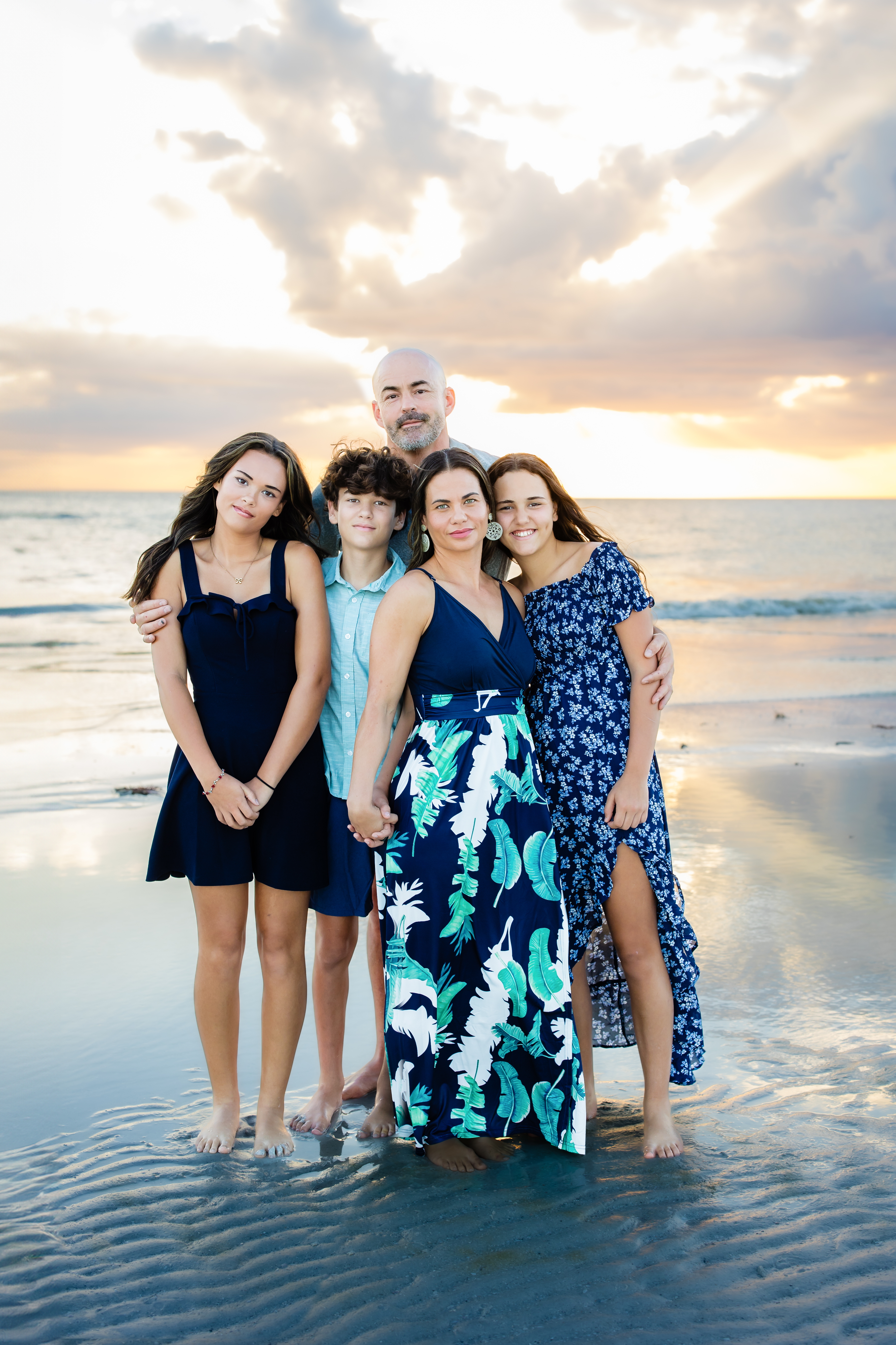 Parents with three kids smiling together for a sunset family photo on the beach in Sarasota
