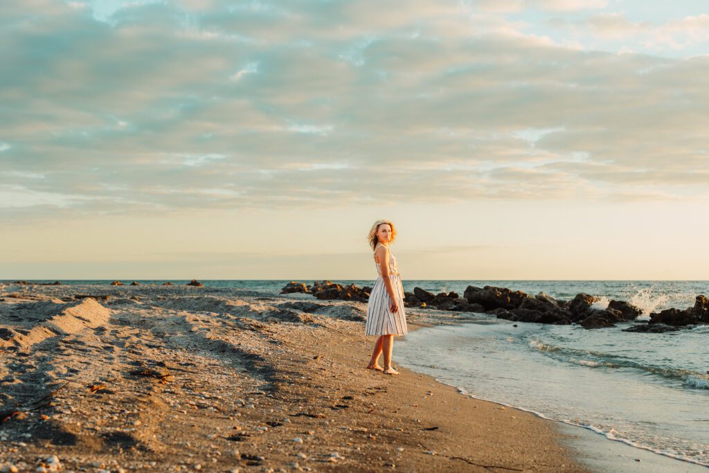 Senior portrait session on rocky Sarasota beach at golden hour