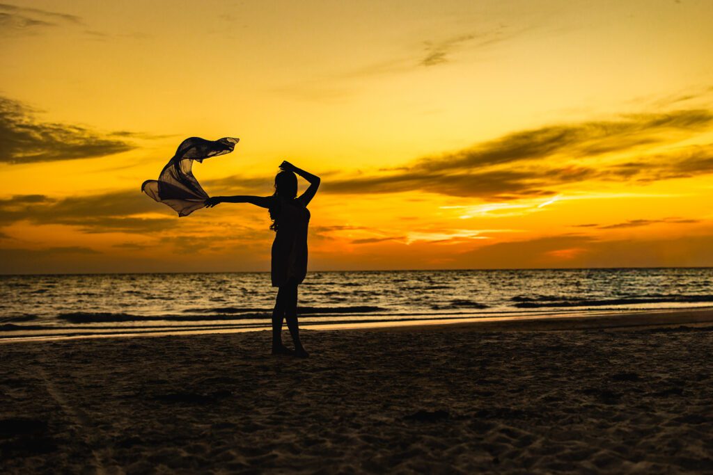 Silhouette of senior portrait session on the beach at sunset in Sarasota Florida, girl with scarf in the wind against golden Gulf Coast sky, Michaela Ristaino Photography