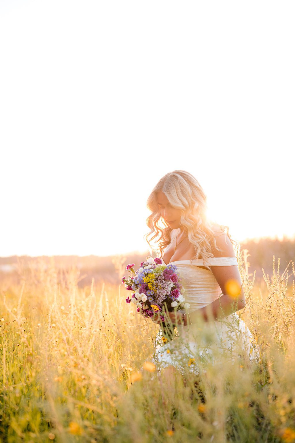 Candid senior portrait at Myakka River State Park Sarasota Florida, girl in white eyelet dress with wildflower bouquet in golden sunset light