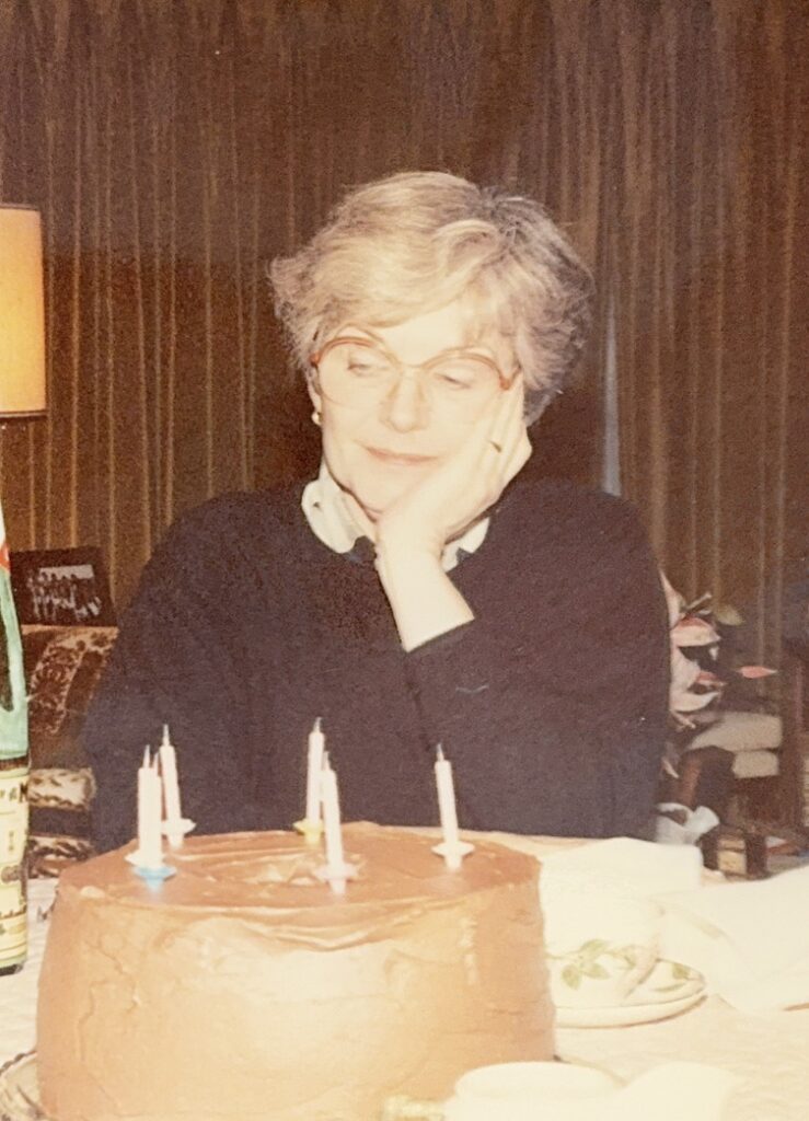 Dori Chaconas at her birthday, thoughtful and present, candles glowing in front of her.