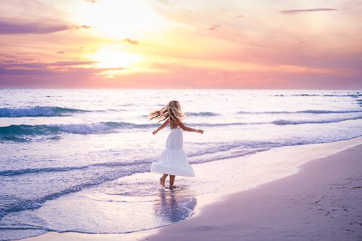 Joyful senior portrait twirling on Sarasota beach at sunse