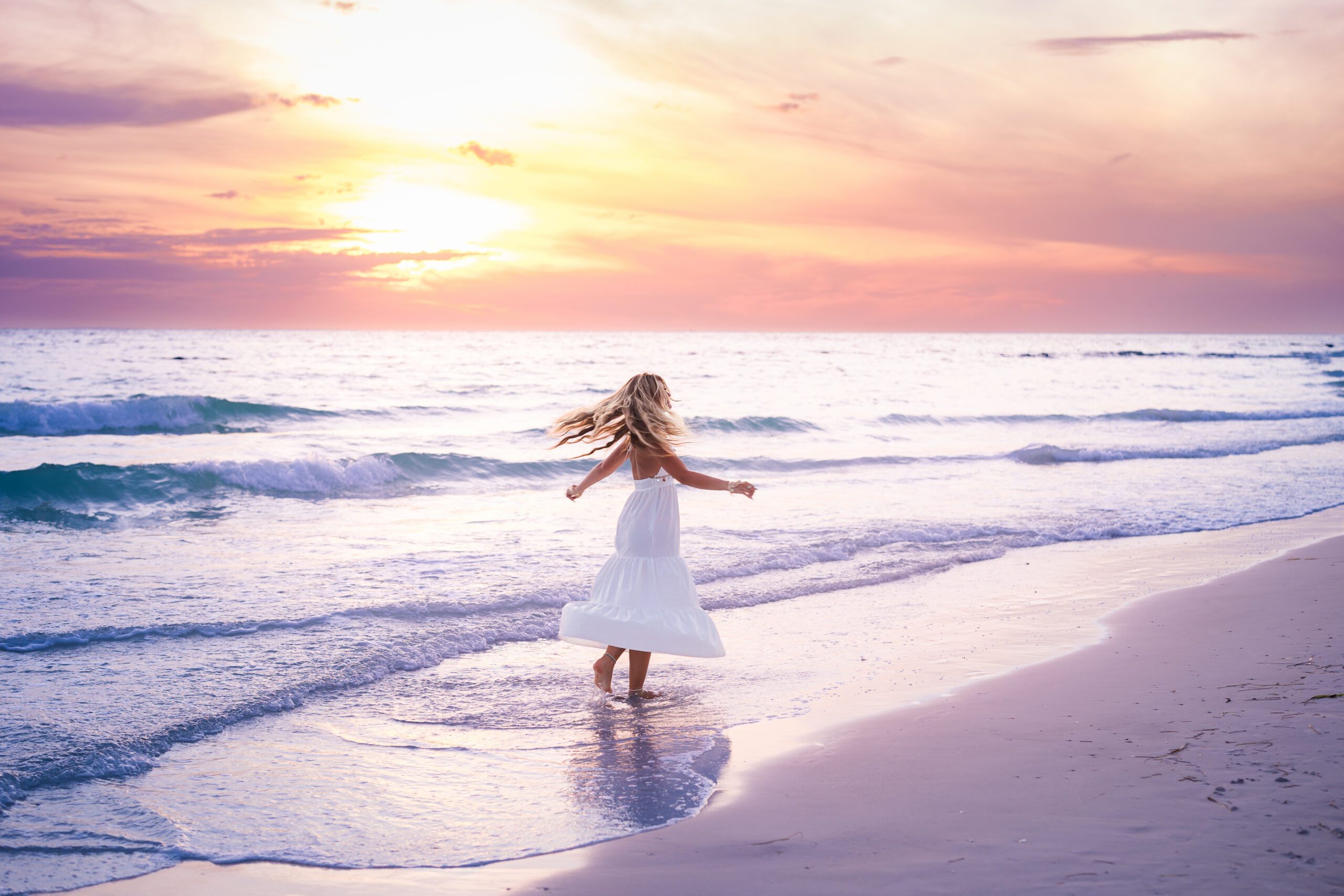 Teen girl in white dress twirling on Sarasota beach at golden hour sunset, senior portrait photography