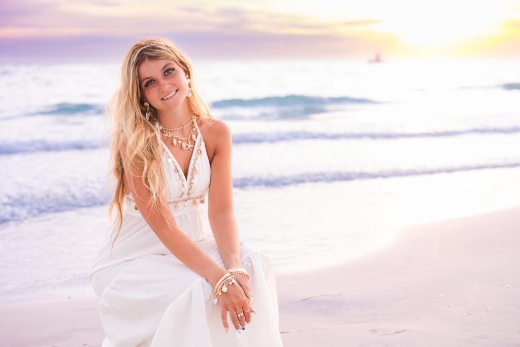 Sarasota senior portrait session at golden hour on Lido Beach, senior laughing candidly with soft ocean bokeh