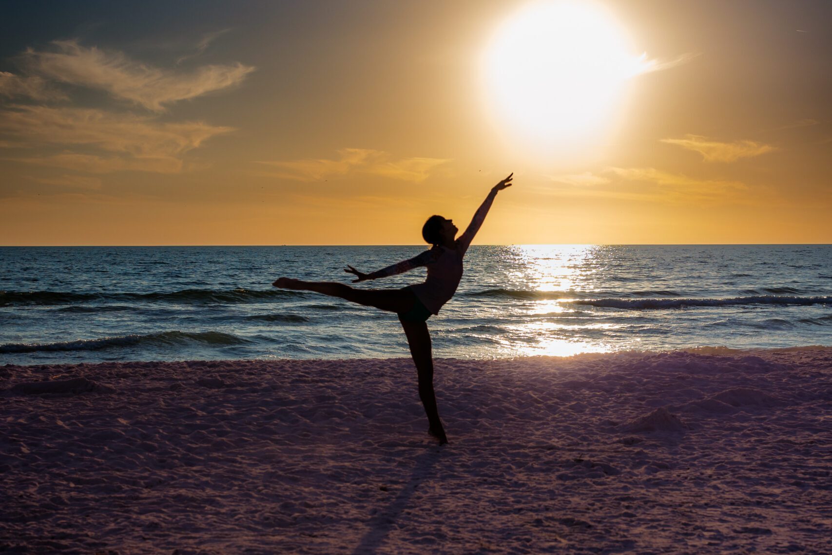 Senior dancer silhouette leaping on Sarasota beach at sunset