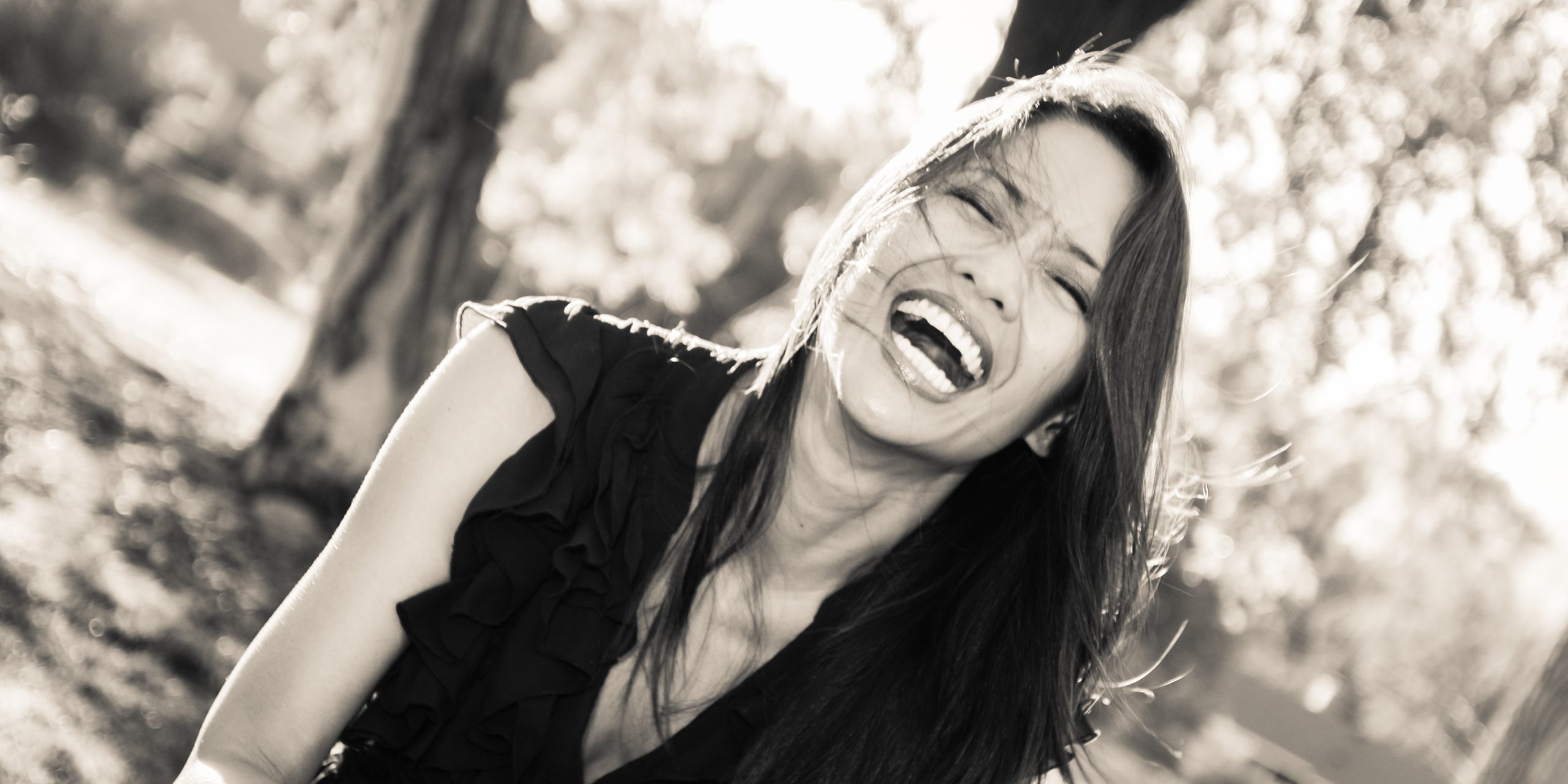 Black and white candid headshot of woman laughing outdoors in Sarasota